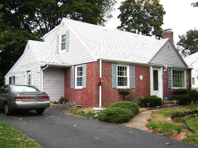 cape cod home with brick siding and a chimney