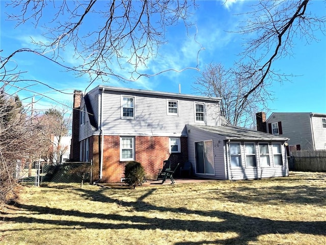 rear view of property with fence, brick siding, a chimney, a patio area, and a lawn