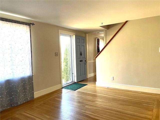 entrance foyer featuring a healthy amount of sunlight, stairs, baseboards, and wood finished floors