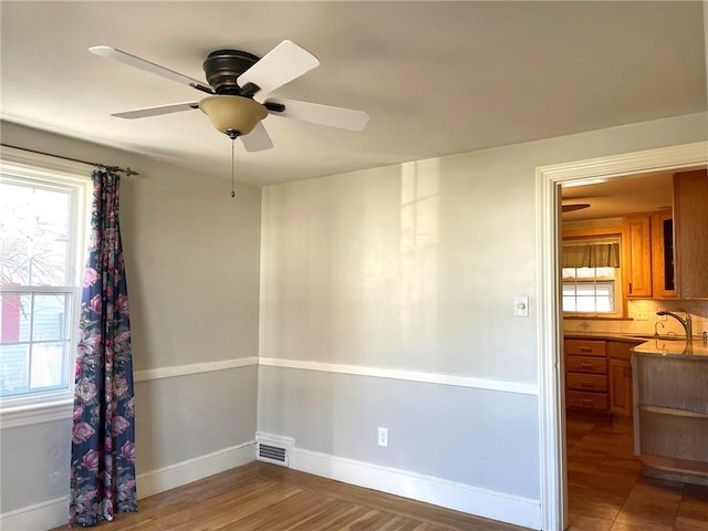 empty room with baseboards, a wealth of natural light, and a sink