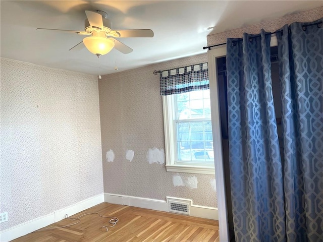 spare room with visible vents, baseboards, wood finished floors, and wallpapered walls