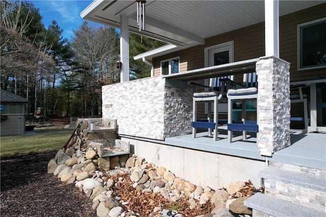 view of side of home with stone siding and a porch