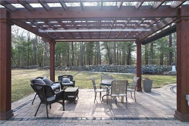 view of patio featuring outdoor dining space, a wooded view, and a pergola