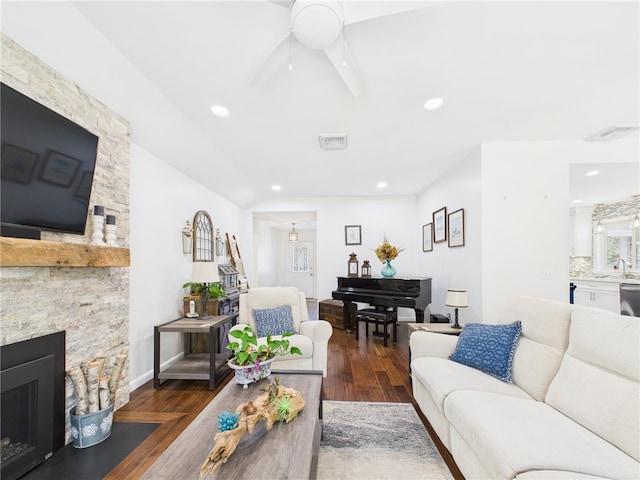 living room with a stone fireplace, recessed lighting, wood finished floors, and visible vents