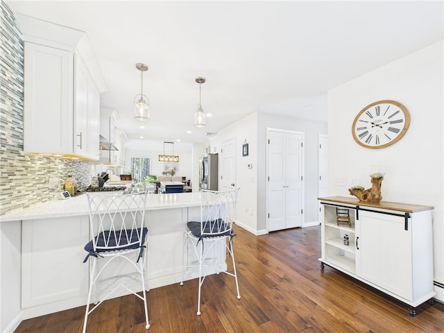 kitchen featuring dark wood-style floors, a peninsula, refrigerator, light countertops, and white cabinets