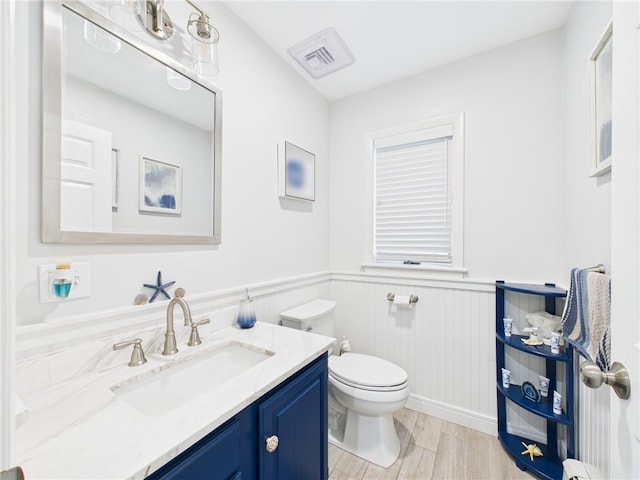 bathroom with visible vents, toilet, wainscoting, wood finished floors, and vanity