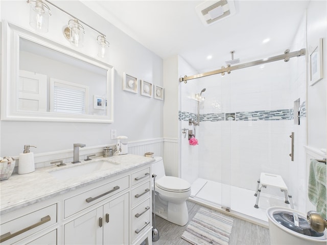 full bathroom featuring visible vents, a wainscoted wall, toilet, a stall shower, and vanity