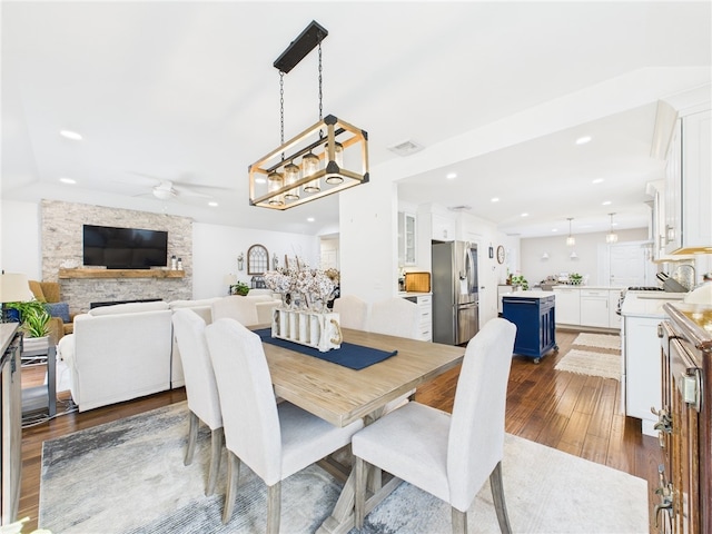 dining room with visible vents, dark wood-style floors, recessed lighting, a stone fireplace, and ceiling fan