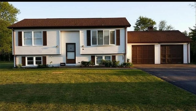 split foyer home featuring aphalt driveway, a garage, a chimney, and a front lawn