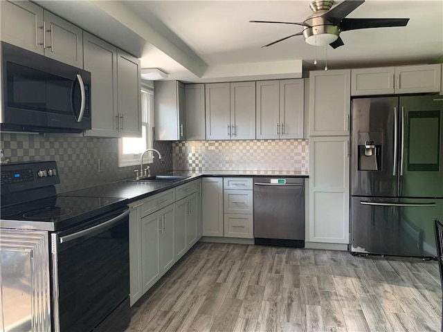 kitchen featuring dark countertops, ceiling fan, gray cabinets, appliances with stainless steel finishes, and a sink