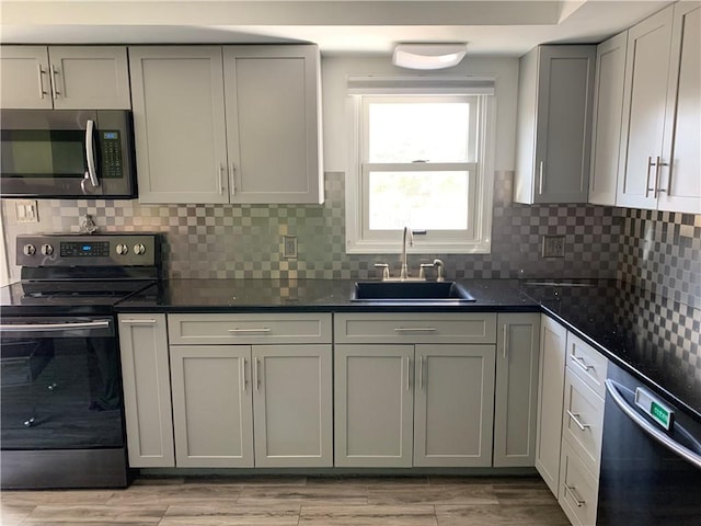 kitchen with stainless steel microwave, light wood-type flooring, electric range oven, dishwashing machine, and a sink