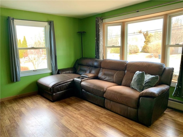 living area featuring a baseboard heating unit, baseboards, and wood finished floors