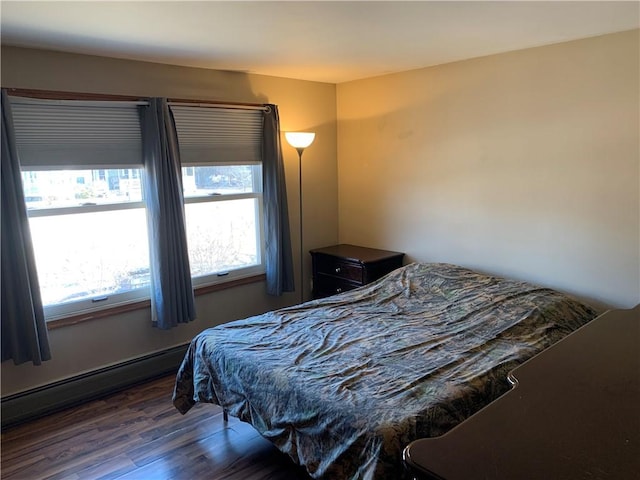 bedroom featuring a baseboard heating unit and wood finished floors