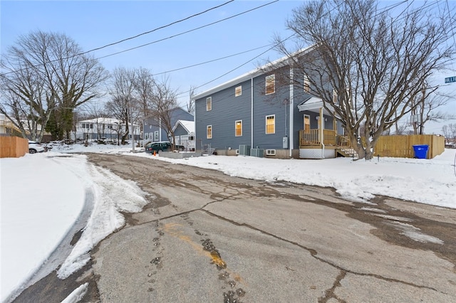 snow covered house featuring a residential view, covered porch, and fence