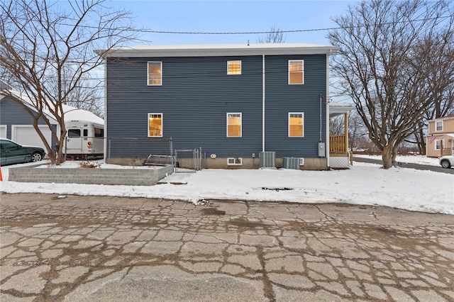 snow covered rear of property featuring central AC unit