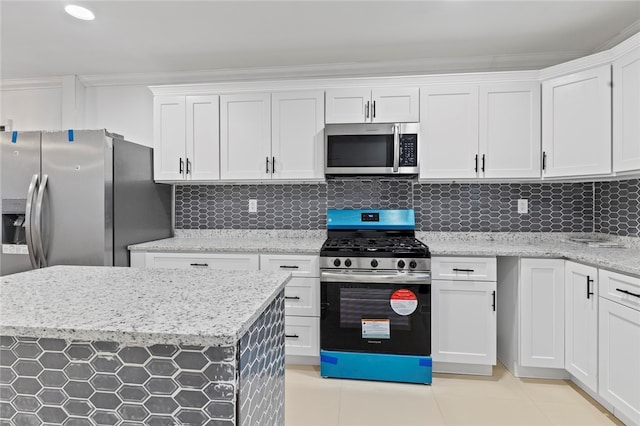 kitchen with light stone counters, light tile patterned floors, stainless steel appliances, decorative backsplash, and white cabinetry