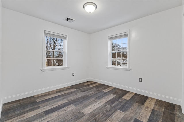 spare room featuring dark wood-type flooring, baseboards, and visible vents