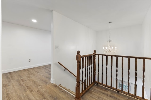 stairway with recessed lighting, baseboards, an inviting chandelier, and wood finished floors