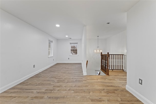 unfurnished room with an inviting chandelier, recessed lighting, light wood-style floors, and baseboards