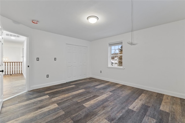 unfurnished room featuring dark wood-style floors, visible vents, and baseboards