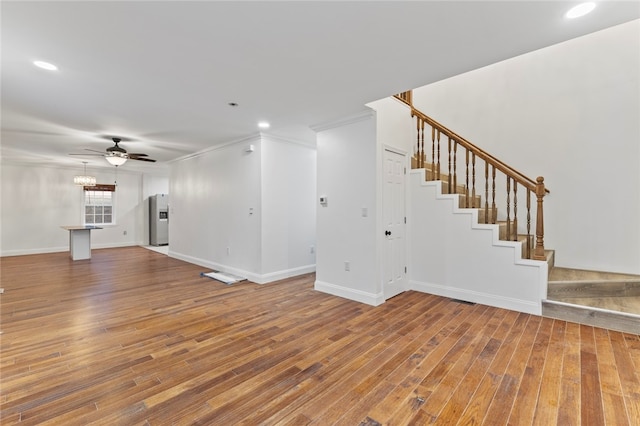 unfurnished living room featuring stairway, ceiling fan, baseboards, and wood-type flooring