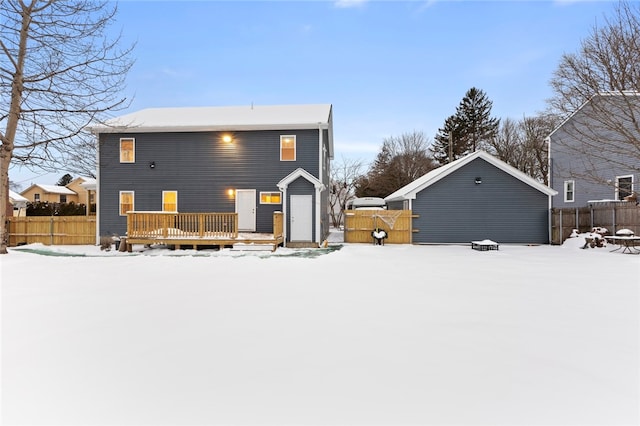 snow covered house featuring a fire pit, fence, and a wooden deck