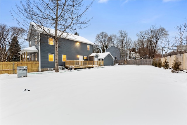 snow covered back of property featuring a wooden deck and a fenced backyard