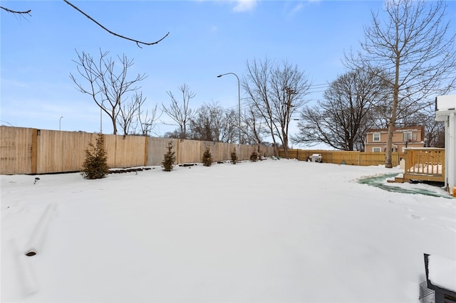 yard layered in snow with a wooden deck and a fenced backyard