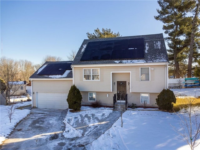 split foyer home with a garage, solar panels, and a shingled roof