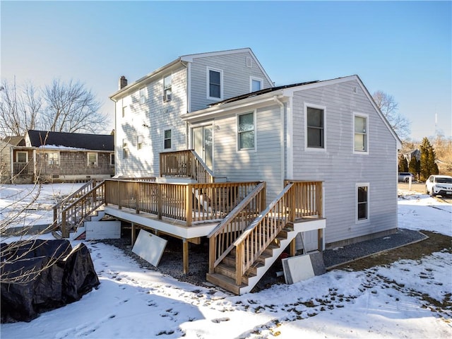 snow covered back of property featuring a wooden deck and stairs