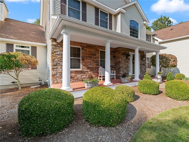 view of exterior entry with stone siding and covered porch