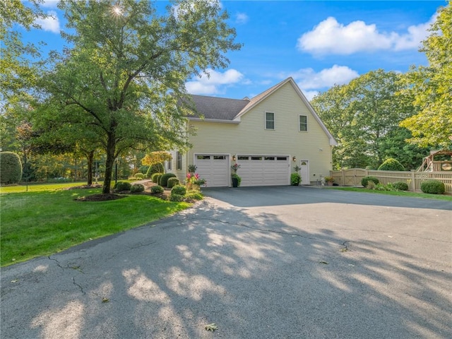 view of front facade featuring aphalt driveway, an attached garage, fence, and a front yard