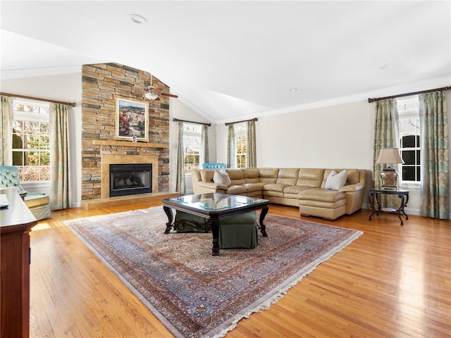 living area with a wealth of natural light, lofted ceiling, light wood-style floors, and a fireplace