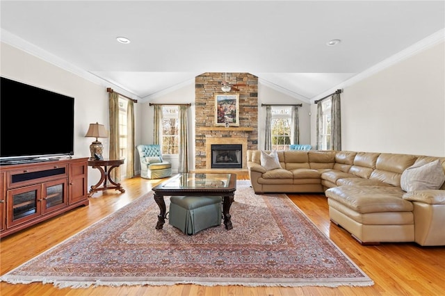 living room featuring a stone fireplace, ornamental molding, wood finished floors, and vaulted ceiling