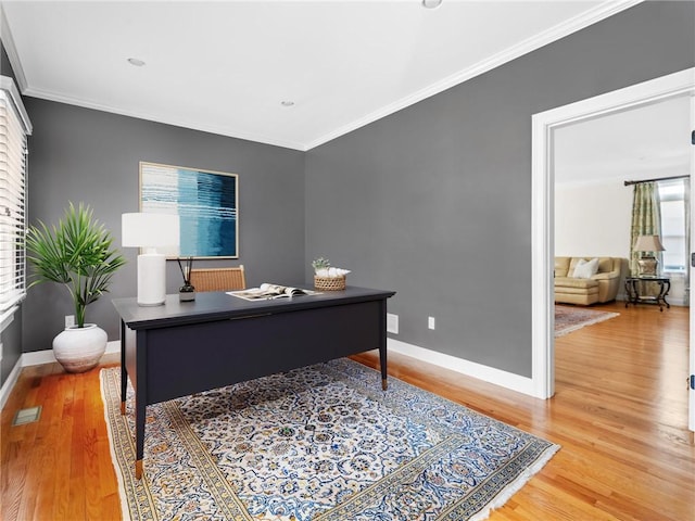 office space featuring visible vents, baseboards, wood finished floors, and crown molding