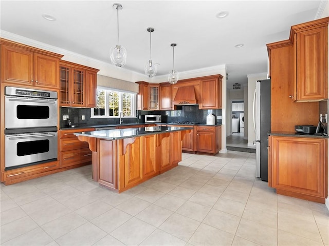 kitchen with premium range hood, stainless steel appliances, tasteful backsplash, and brown cabinetry