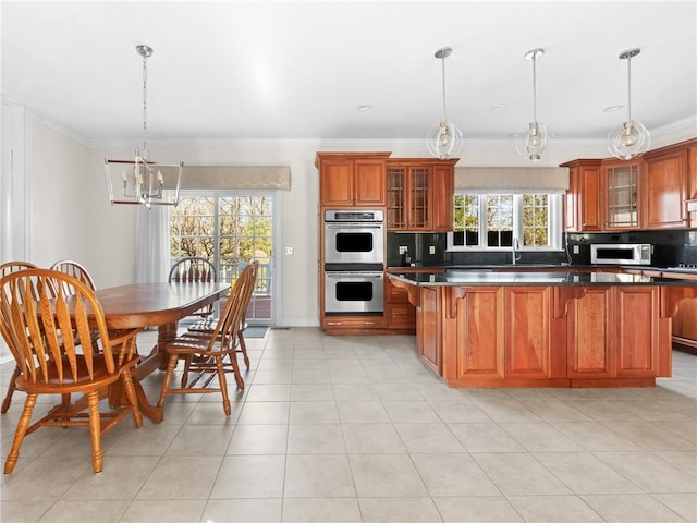 kitchen featuring crown molding, a kitchen bar, decorative backsplash, brown cabinets, and appliances with stainless steel finishes