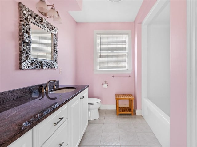 full bathroom with tile patterned floors, toilet, a bathing tub, baseboards, and vanity