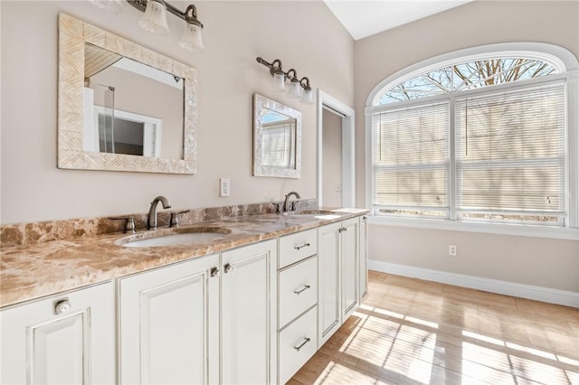 bathroom with a sink, baseboards, and double vanity