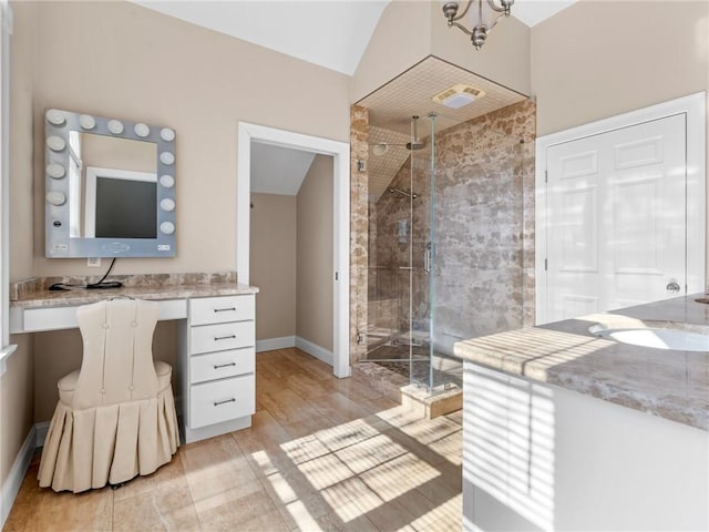 full bath with a stall shower, vanity, baseboards, and vaulted ceiling