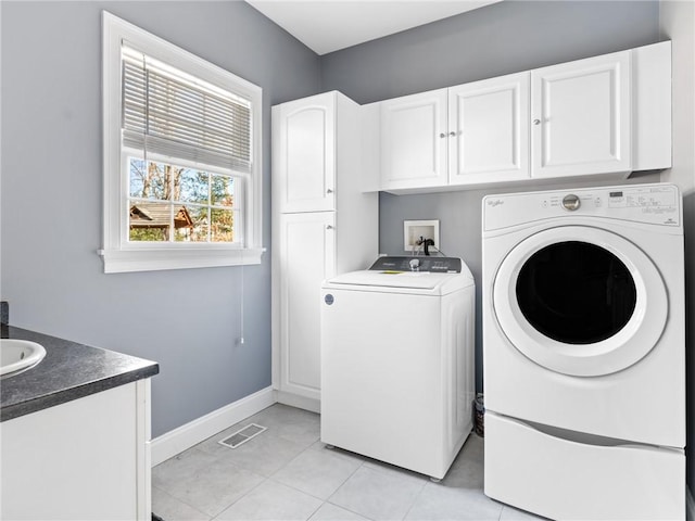 laundry room with visible vents, baseboards, light tile patterned floors, washer and dryer, and cabinet space