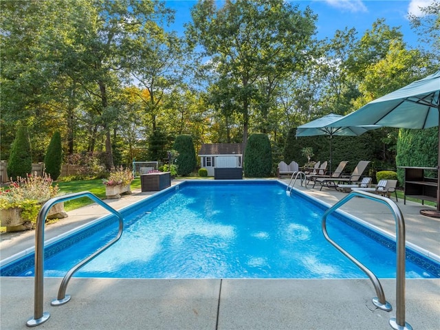 outdoor pool with a fenced backyard, a patio, an outdoor structure, and a shed