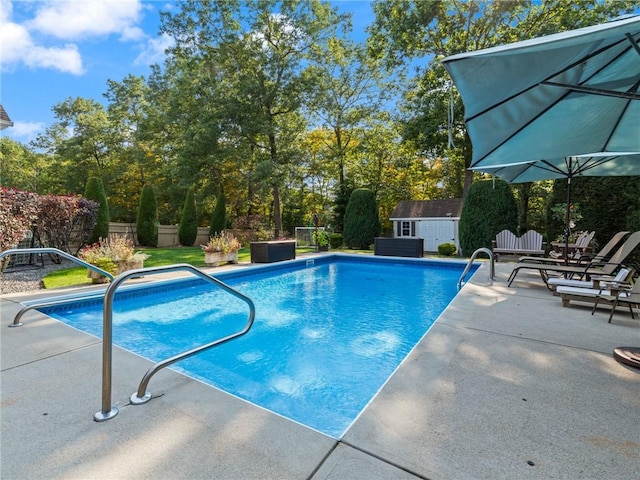 outdoor pool with fence, an outbuilding, a shed, and a patio area