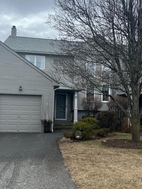 view of front facade featuring an attached garage, driveway, and a chimney