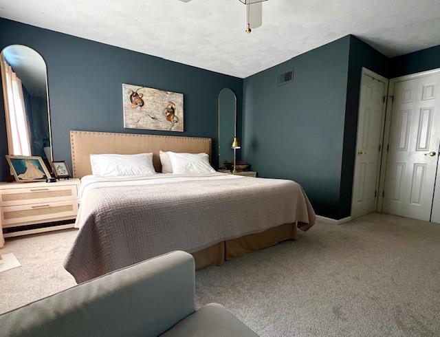 bedroom featuring arched walkways, visible vents, carpet flooring, and ceiling fan