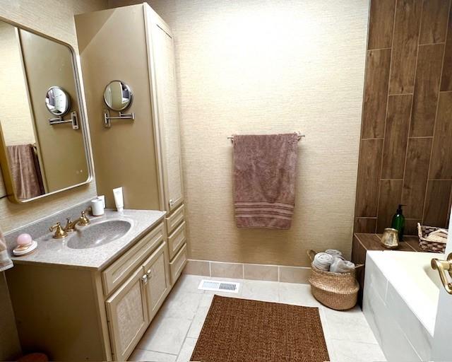 full bathroom with tile patterned floors, visible vents, a bathing tub, and vanity