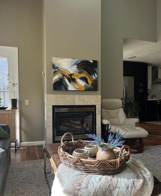 living room featuring a tiled fireplace, wood finished floors, and baseboards