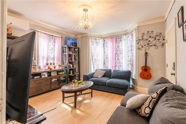 living area featuring baseboards, a notable chandelier, an AC wall unit, and light wood finished floors