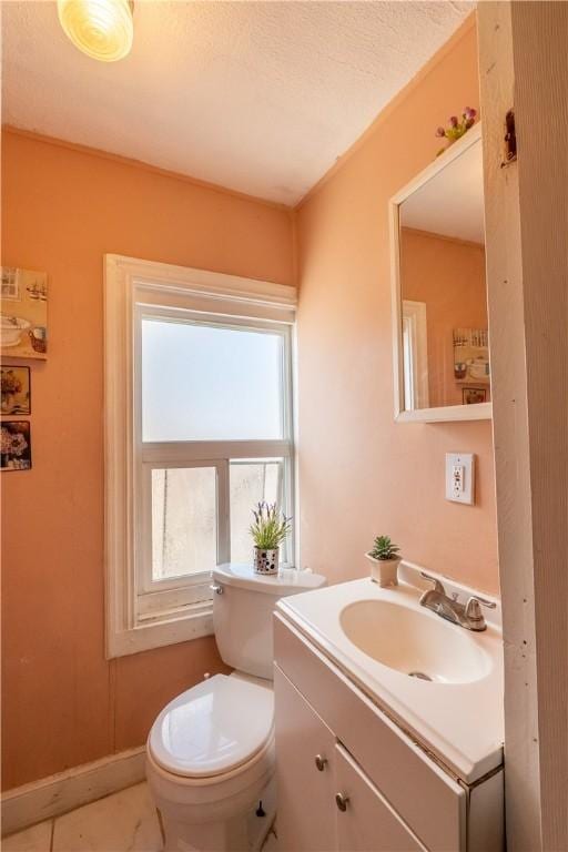 bathroom with toilet, vanity, and baseboards