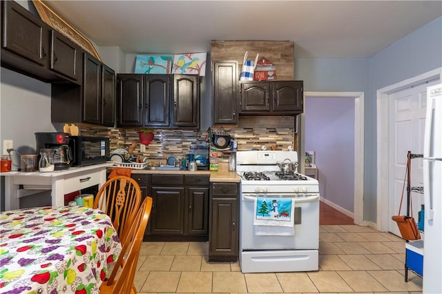 kitchen featuring white range with gas cooktop, light countertops, light tile patterned floors, decorative backsplash, and dark brown cabinets